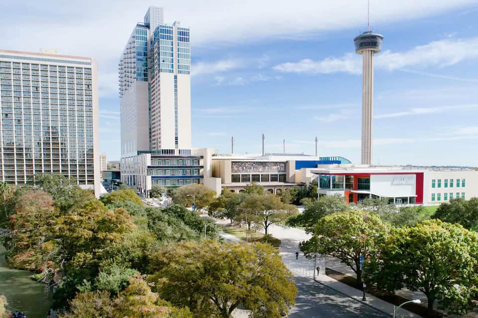 Urban cityscape with tall buildings, observation tower, and green park area