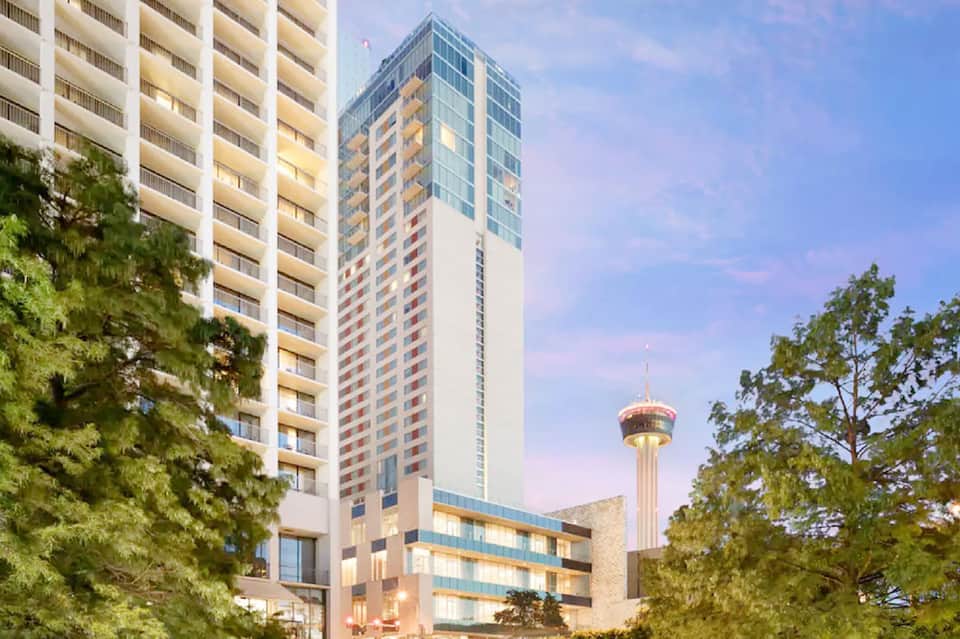 Tall residential high-rise hotel building with balconies overlooking city skyline and tower landmark