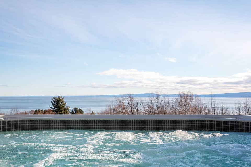 Infinity pool overlooking a tranquil lake with bare winter trees on the shoreline