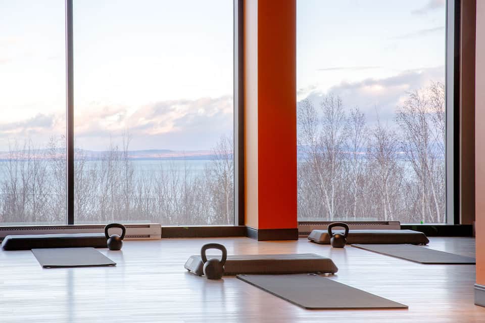 Modern fitness studio with kettlebells, yoga mats, and large windows overlooking winter landscape