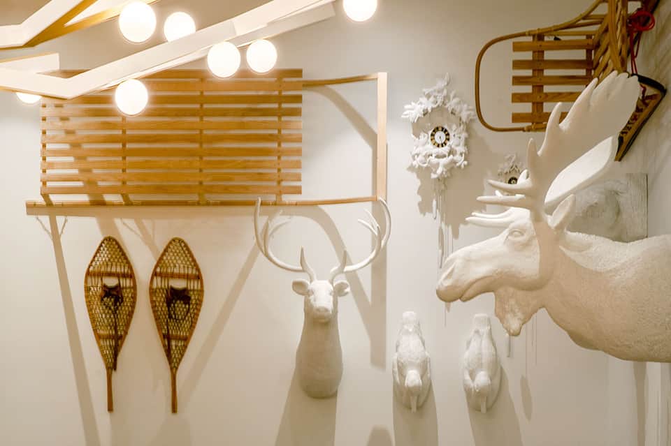 Modern gallery interior with white sculptures, snowshoes, and decorative antlers
