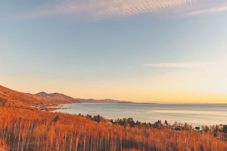 Scenic sunset view of mountains and water with forested shoreline and calm lake