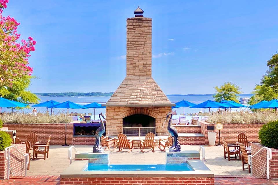 Brick fireplace by the beach with blue umbrellas, Adirondack chairs, and ocean view