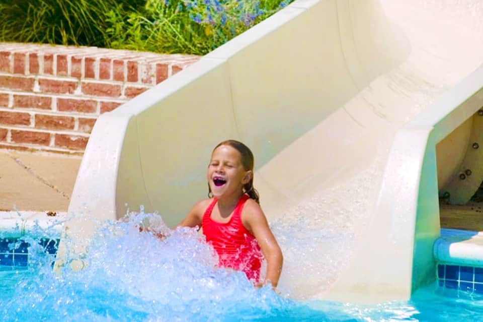 Child enjoying water slide at resort pool with splash and excitement