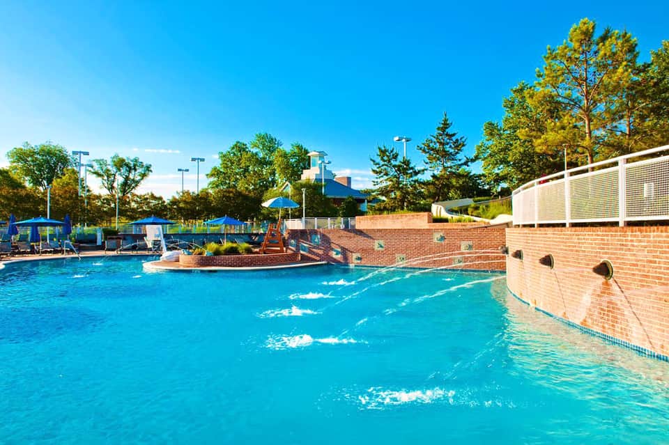 Outdoor community pool with water features and brick buildings