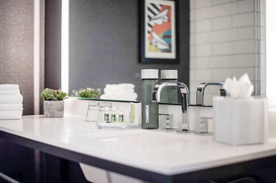 Modern bathroom vanity with white sink, faucet, and toiletries on white countertop