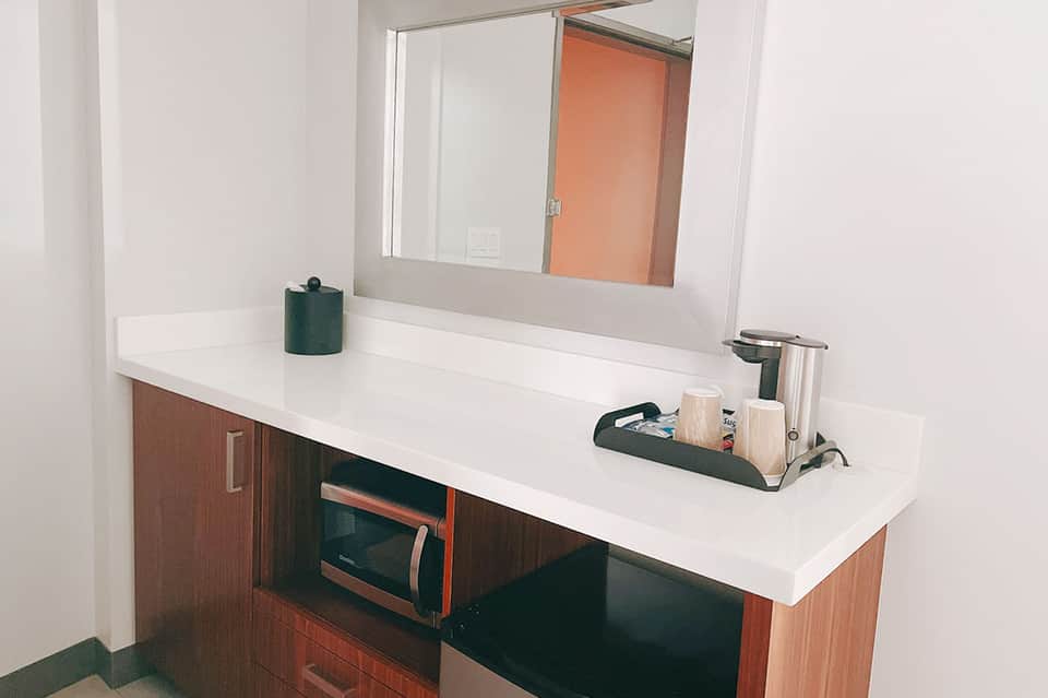 Modern bathroom vanity with white countertop, wooden cabinets, and large mirror