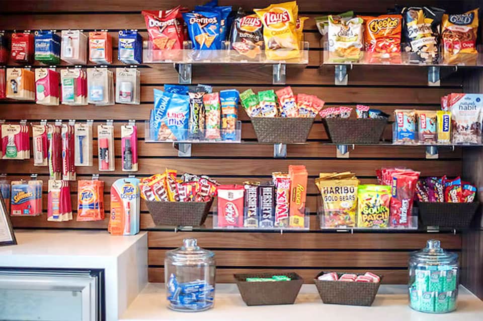 Wooden shelving display stocked with packaged snacks, candies, and beverages in resort convenience store