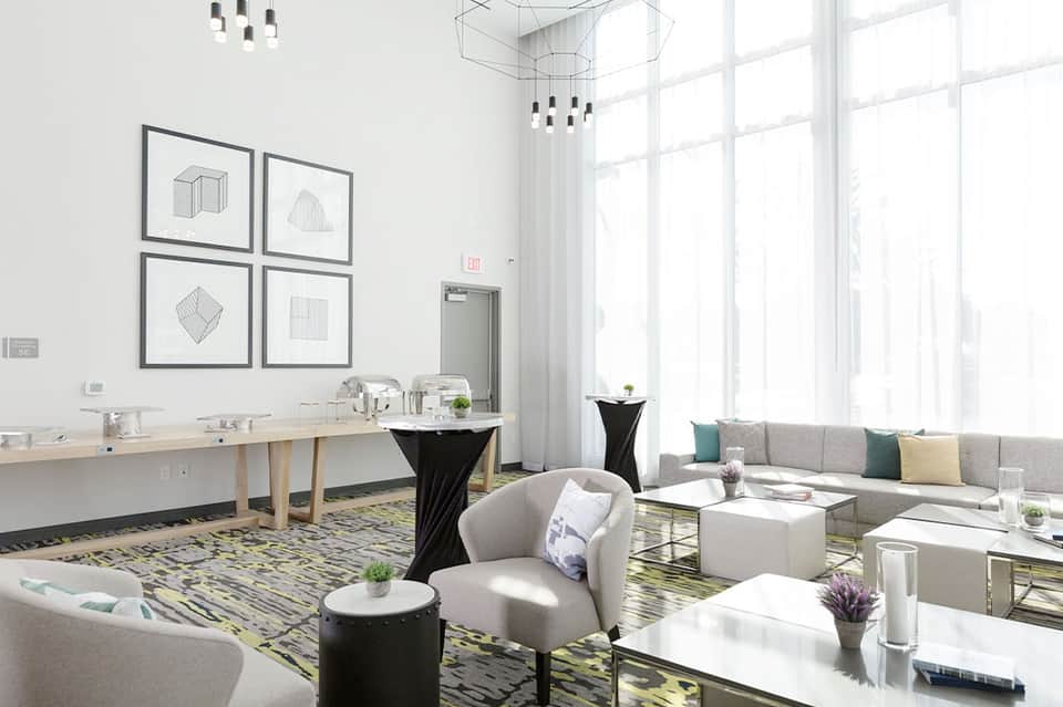 Contemporary hotel lounge with seating areas, geometric wall art, large windows, and modern decor