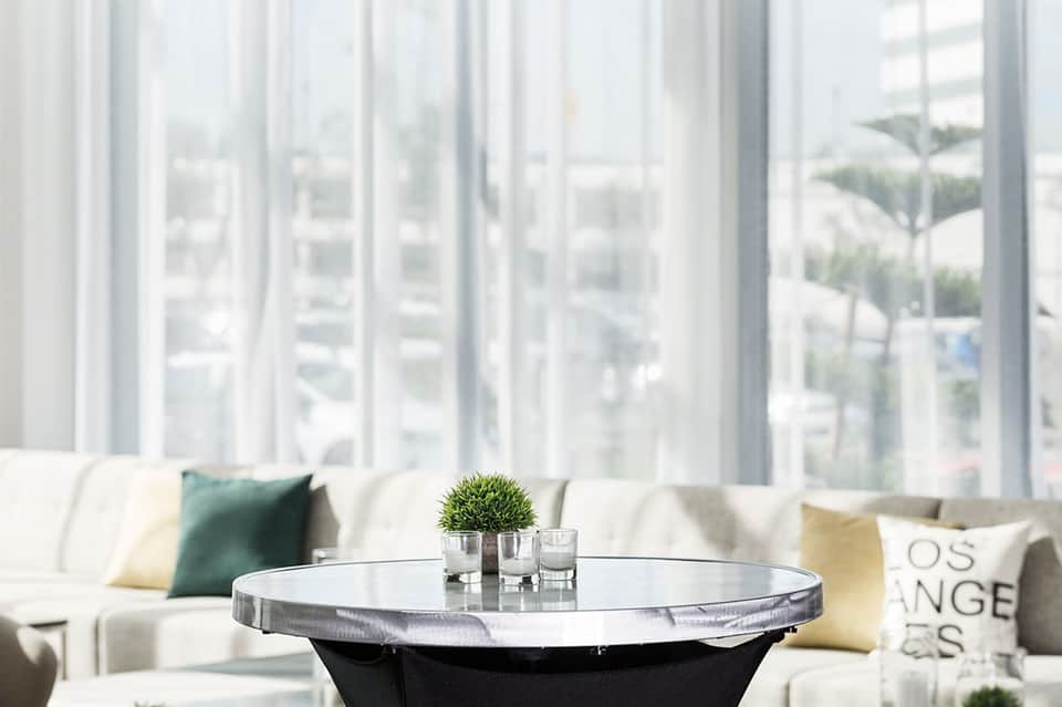 Minimalist lounge area with white sofa, round side table, and expansive windows overlooking palm trees