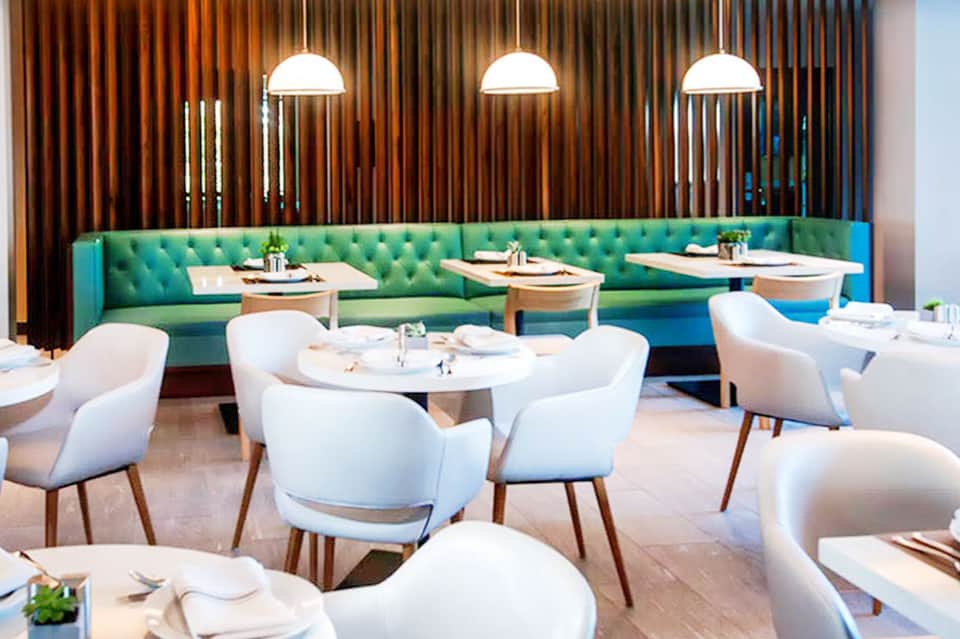 Modern dining room with green tufted banquette seating and contemporary white chairs