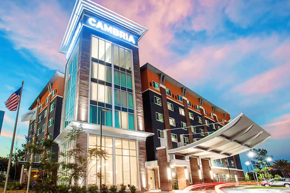 Modern Cambria hotel exterior at dusk with illuminated signage and brick architecture
