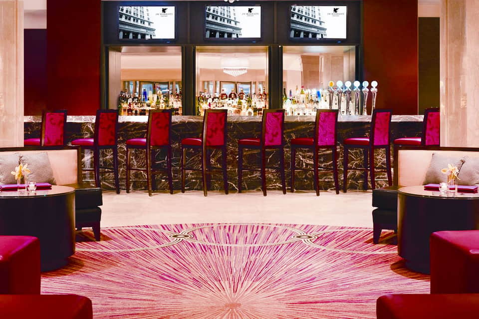 Luxury jewelry store interior with magenta velvet chairs, display cases, and three large screens above storefront windows