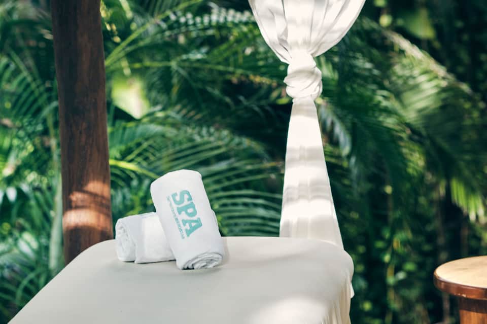 White spa towels rolled on table with tropical palm leaves in background