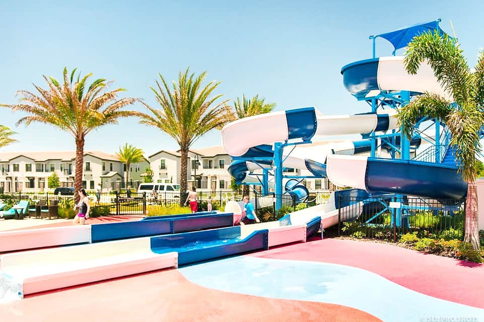 Colorful mini golf course with blue slides and pink surfaces near residential buildings