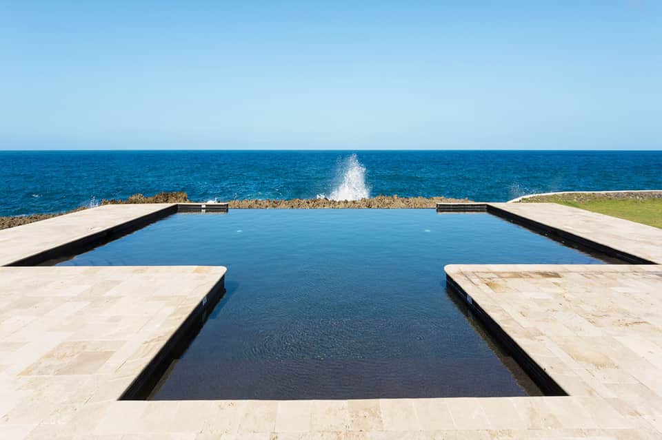 Geometric infinity pool overlooking ocean cliffs with waves crashing beyond the horizon