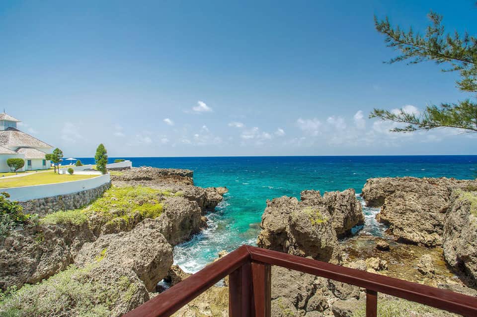 Turquoise ocean cove with rocky limestone formations and white waterfront building