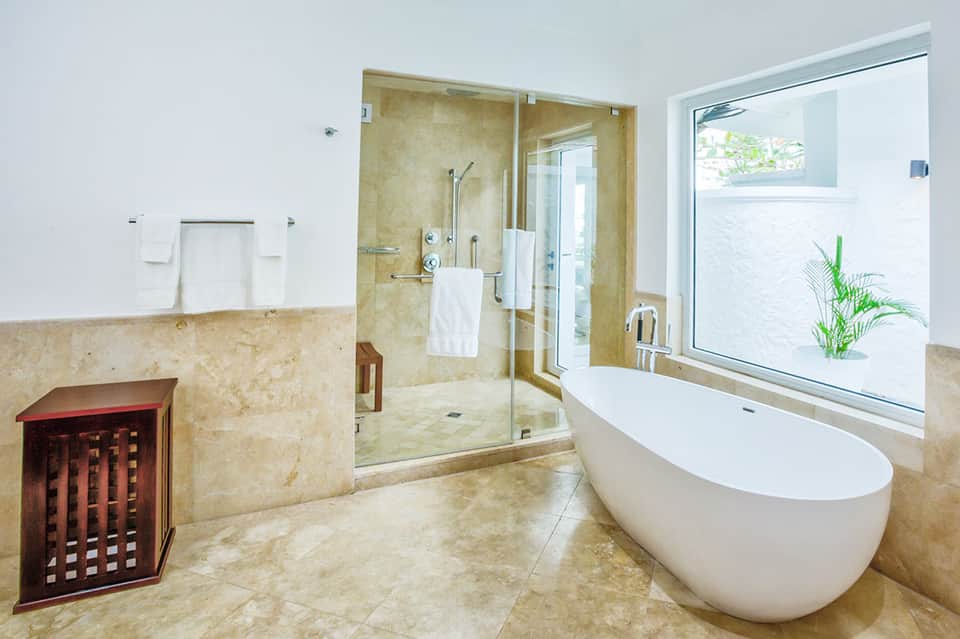 Luxury bathroom with freestanding white tub, large walk-in shower, and natural stone accents