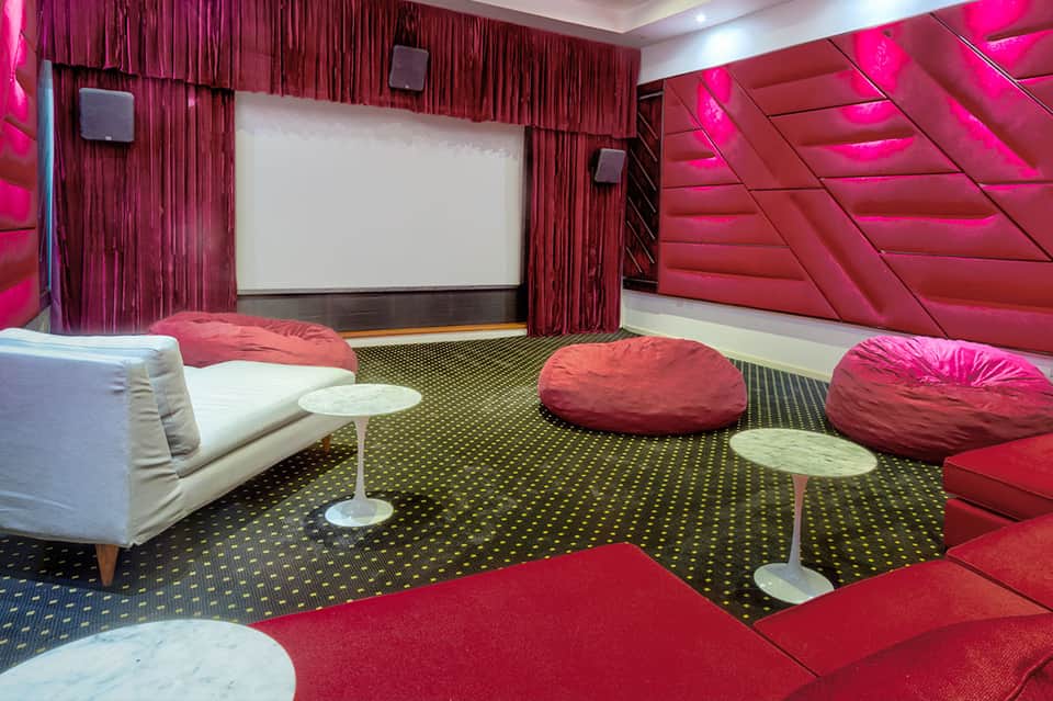 Home theater room with magenta curtains, bean bag seating, and projection screen