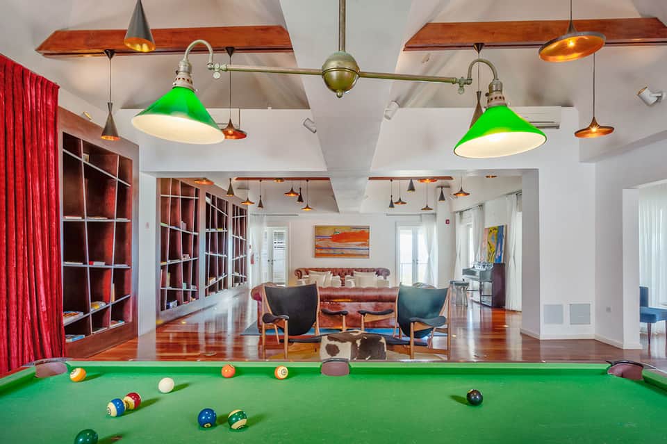 Game room with billiards table, green lamps, red curtains, and colorful interior design