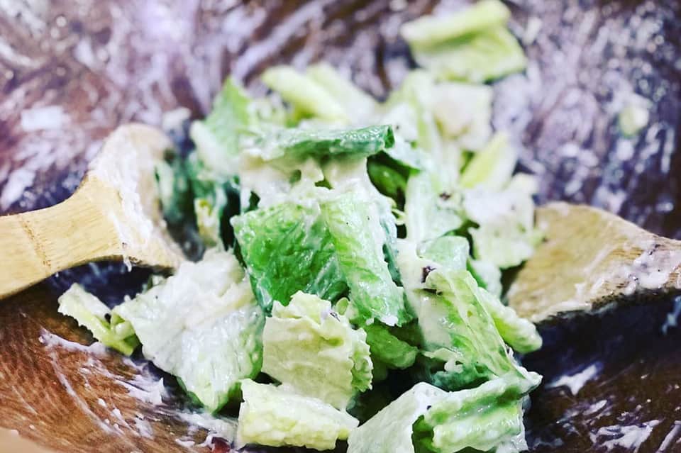 Chopped lettuce and vegetables on wooden cutting board during food preparation