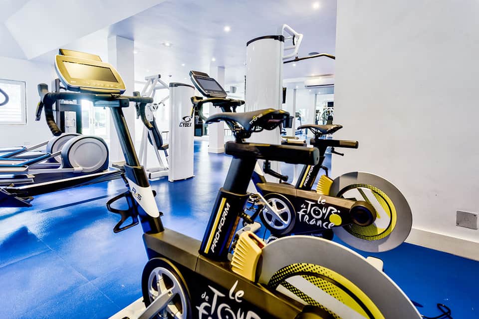 Fitness center with stationary bikes, treadmills, and other exercise equipment with blue floor