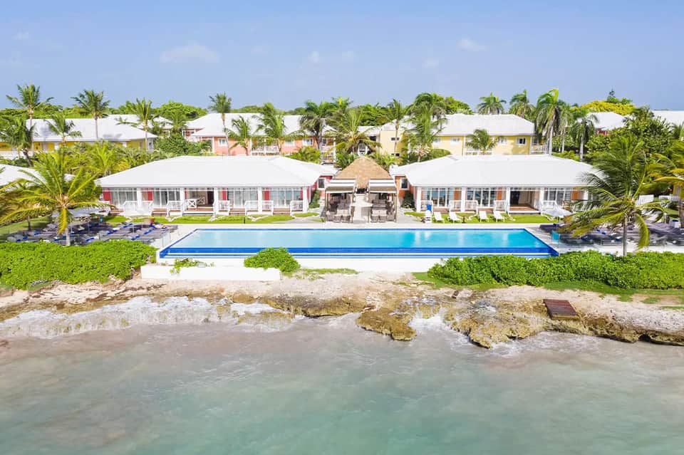 Beachfront resort with rectangular pool, white cabanas, and turquoise ocean waters beyond