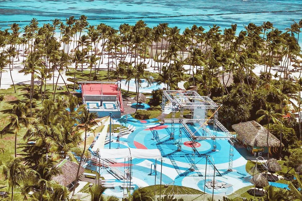Aerial view of colorful water park with slides, pools, and palm trees near beach