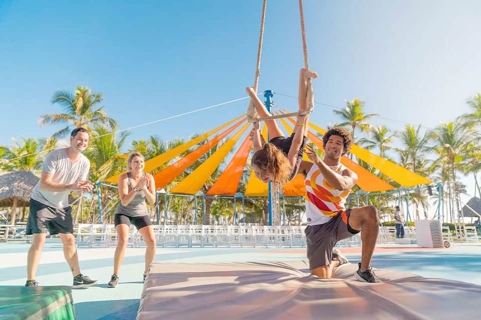 Group of people doing obstacle course training under orange and yellow striped tent