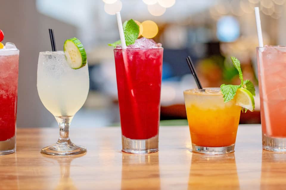 Colorful cocktails with mint and citrus garnishes on wooden bar counter