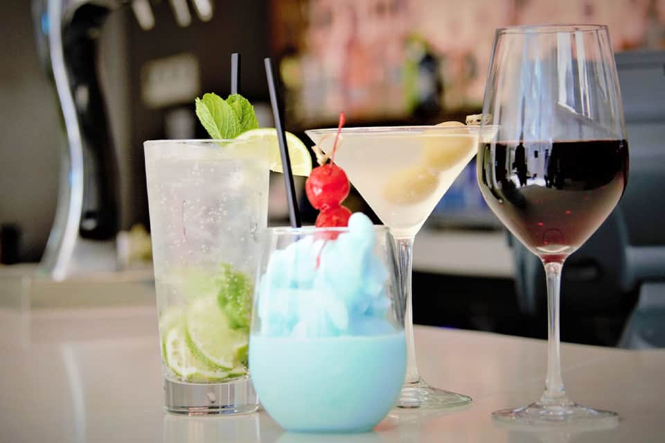 Three colorful cocktails on a bar counter - mojito, blue cocktail, and red wine