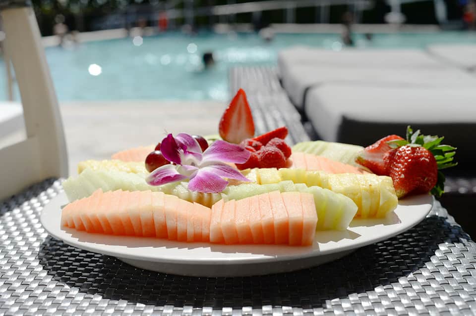 Elegant fruit and sashimi platter with flowers by pool area