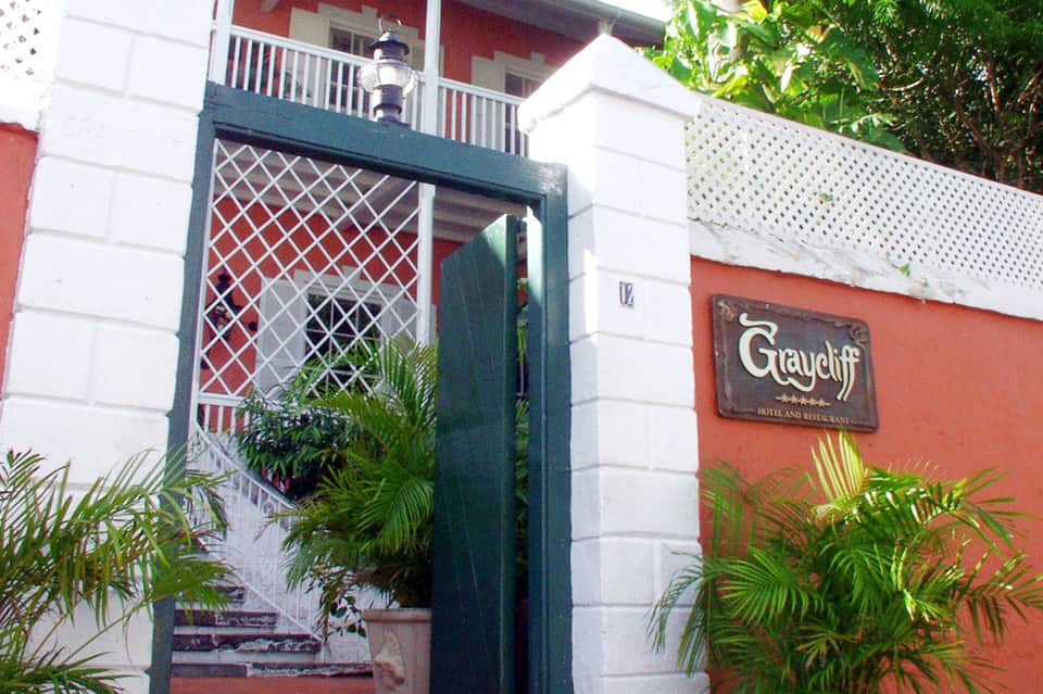Colonial-style hotel entrance with white pillars, red painted walls, and green lattice gate accents