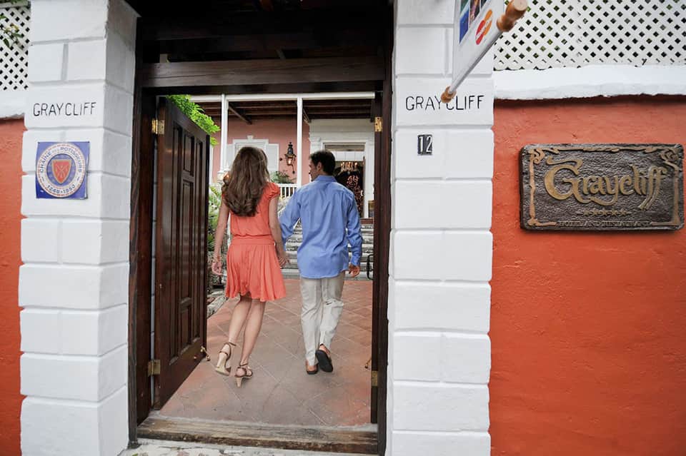 Couple walking through terracotta-colored colonial building entrance marked Graycliff