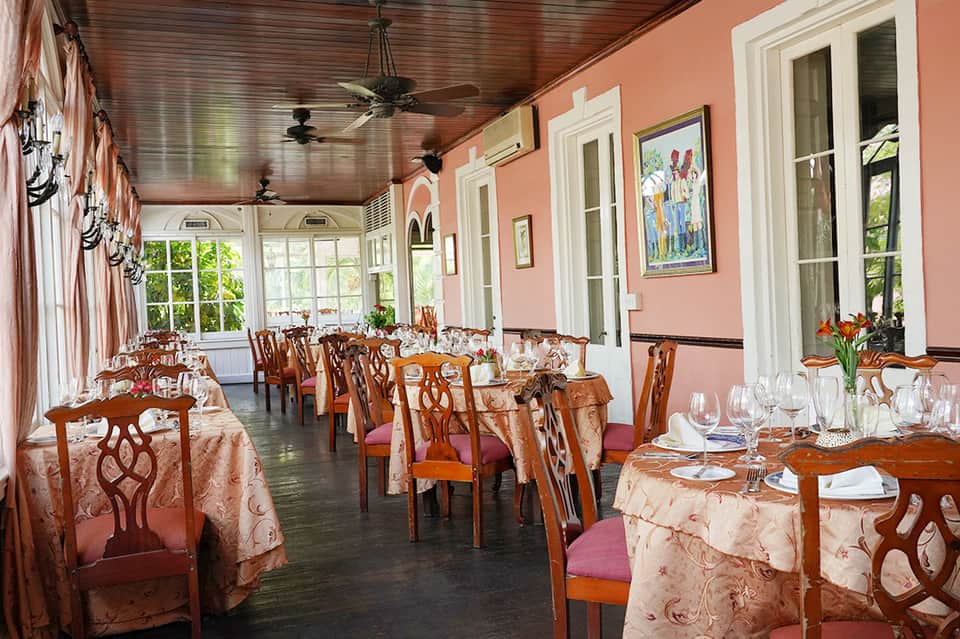 Elegant dining room with pink walls, wooden furniture, and ocean views through windows