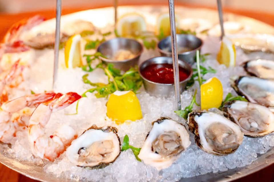 Oysters and shrimp on ice with lemon wedges and cocktail sauce for dipping