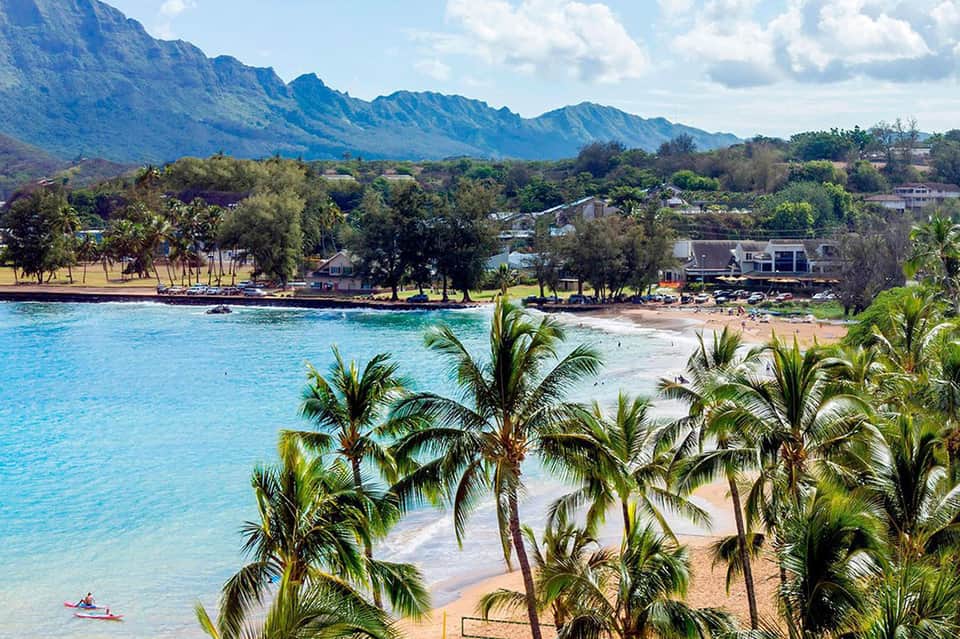 Scenic tropical beach with turquoise water, palm trees, and mountains in background
