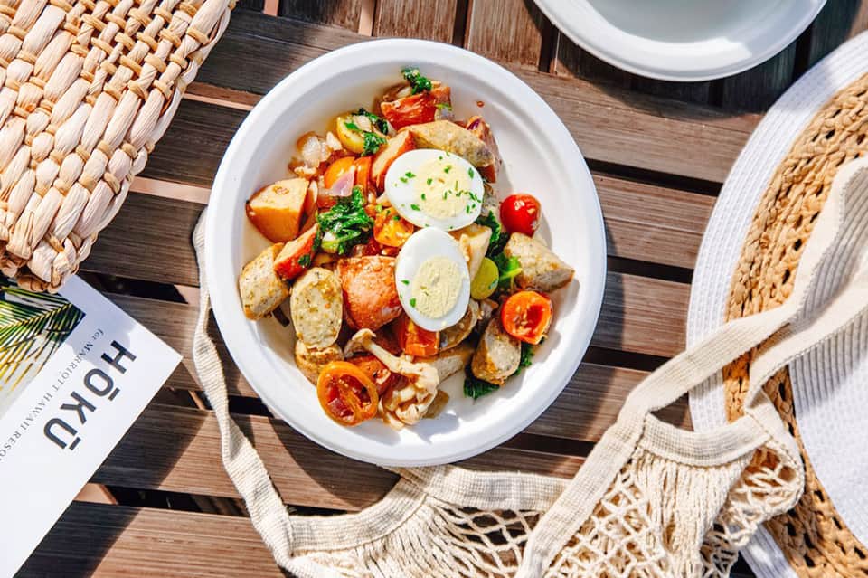Gourmet salad plate with potatoes, greens, and egg on wooden table