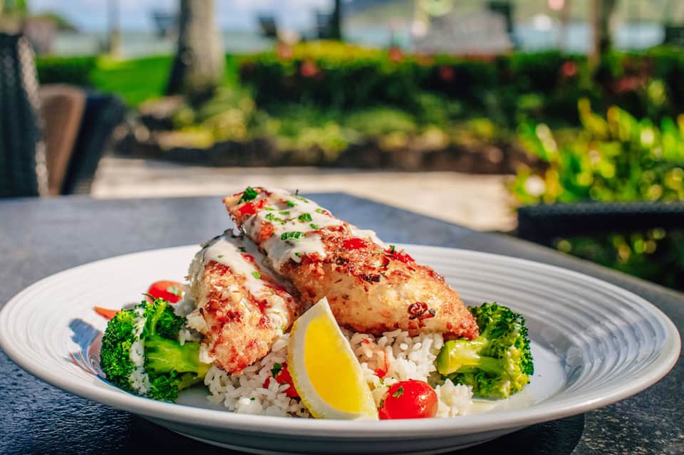 Lobster tail dish with rice, broccoli, and lemon wedge served outdoors