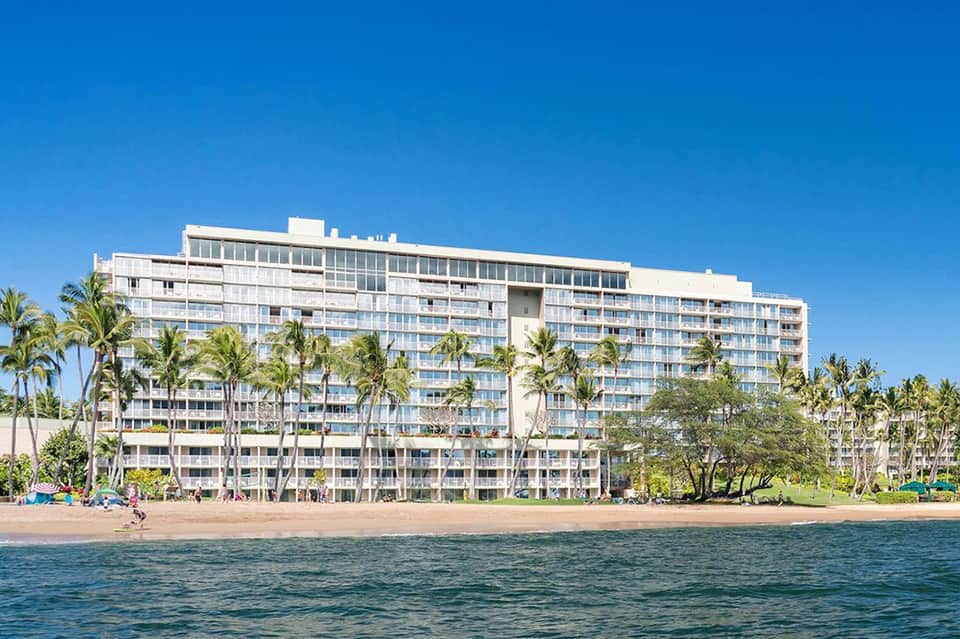 Multi-story beachfront hotel building with palm trees and sandy beach