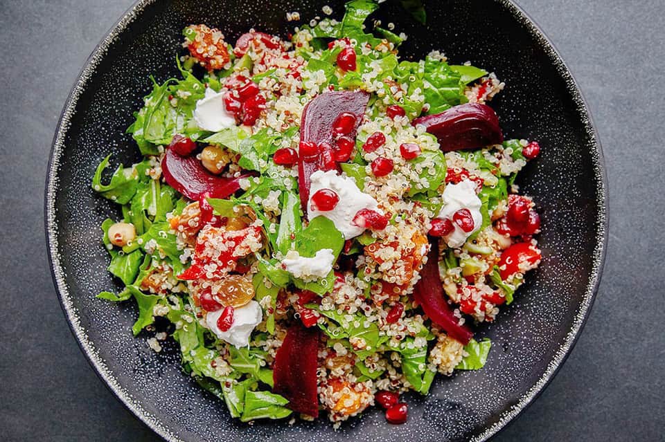 Vibrant quinoa salad with roasted vegetables and herbs on dark textured plate