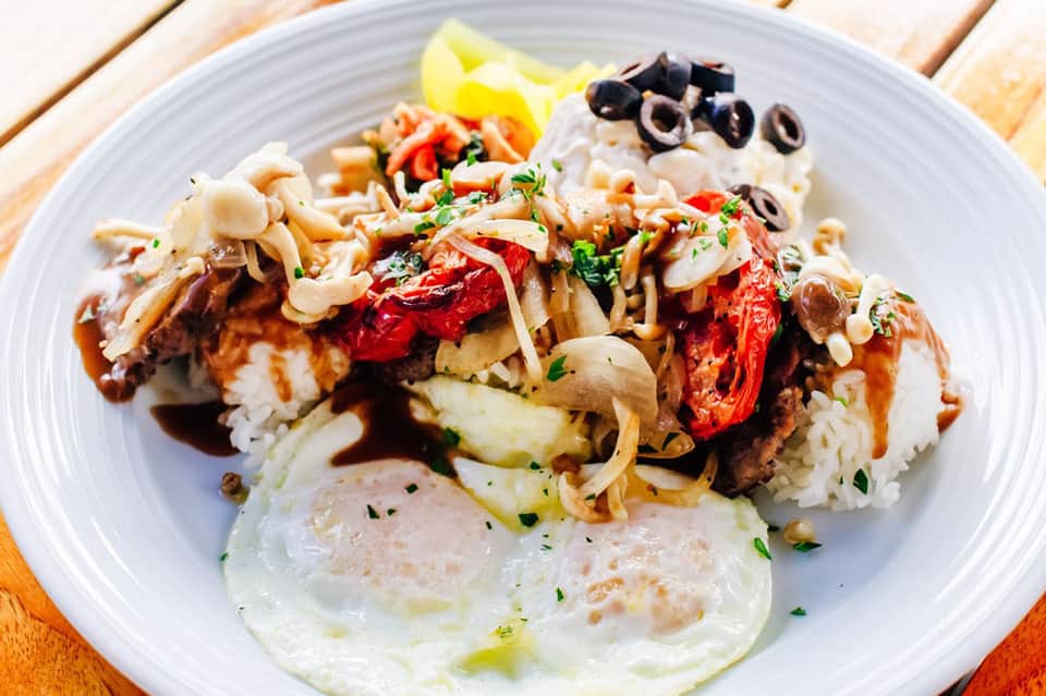 Asian noodle dish with vegetables and protein on white plate at poolside dining