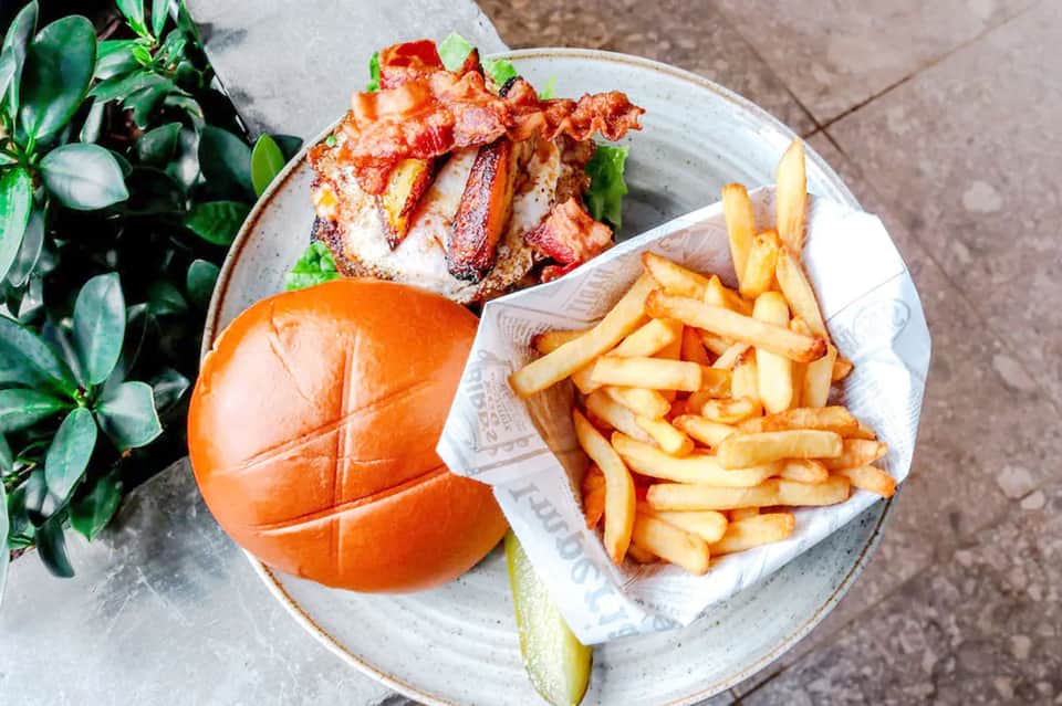 Gourmet burger with fries and fresh lime on a white plate outdoors