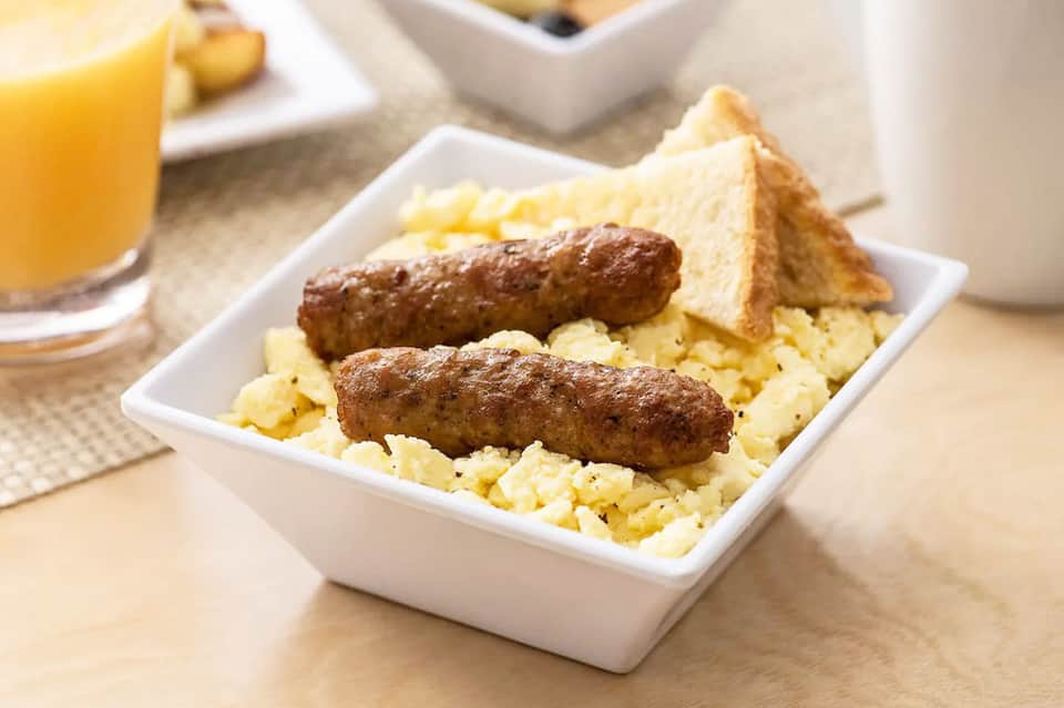 Breakfast plate with sausages, scrambled eggs, toast, and orange juice
