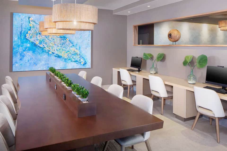 Modern office space with conference table, workspace stations, map display, and wooden accent lighting