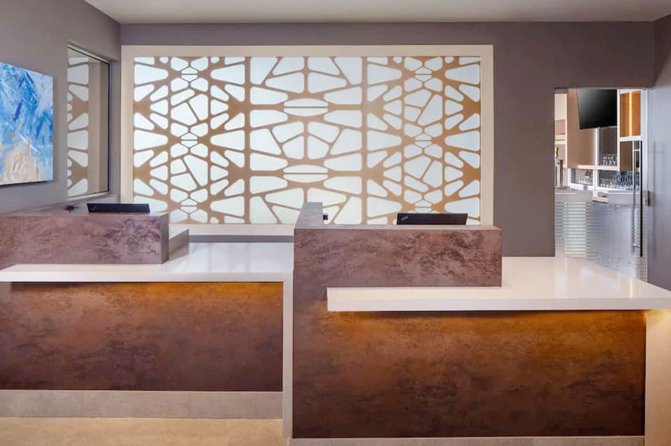 Modern hotel reception desk with earth-tone finishes and decorative lattice window