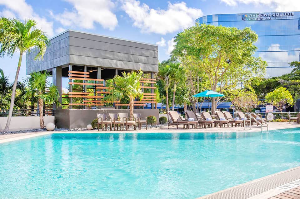 Modern pool area with geometric architecture, lounge seating, and Arizona College of Nursing building in background