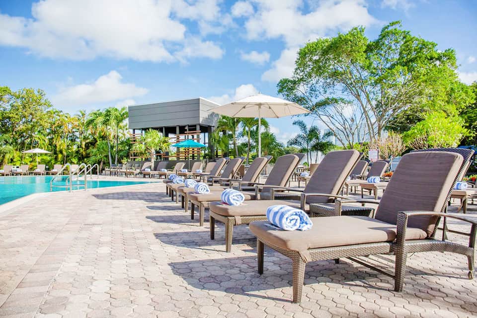 Resort poolside with lounge chairs, umbrellas, and lush tropical landscaping