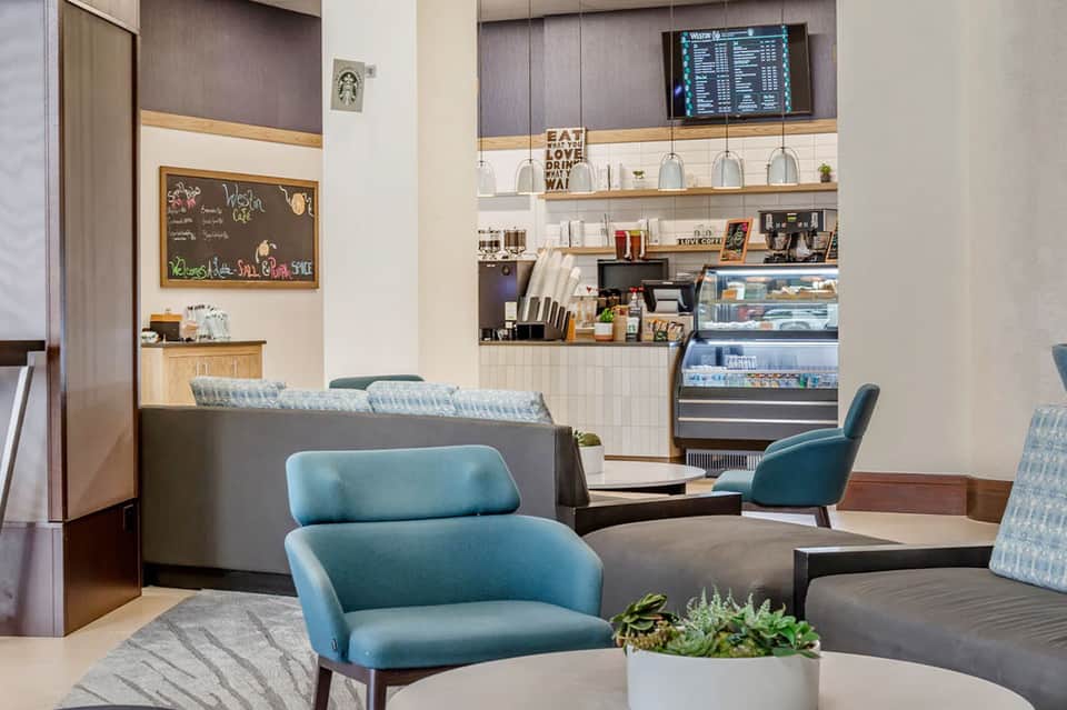 Modern hotel lobby lounge with turquoise chairs and coffee bar