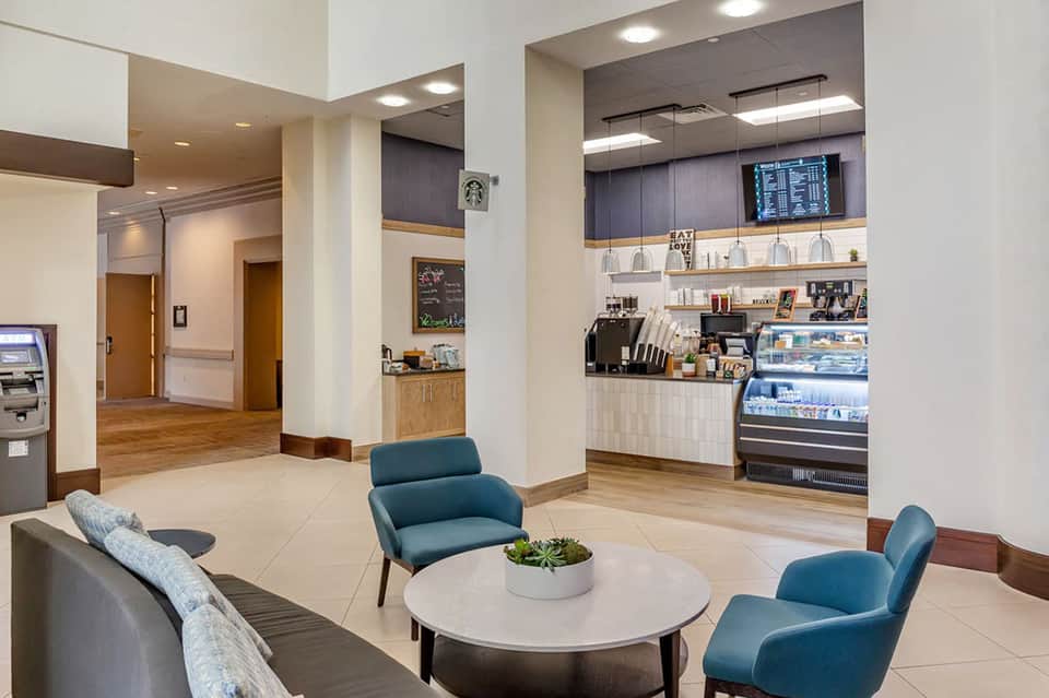 Modern hotel lobby lounge with blue chairs, coffee bar, and seating areas